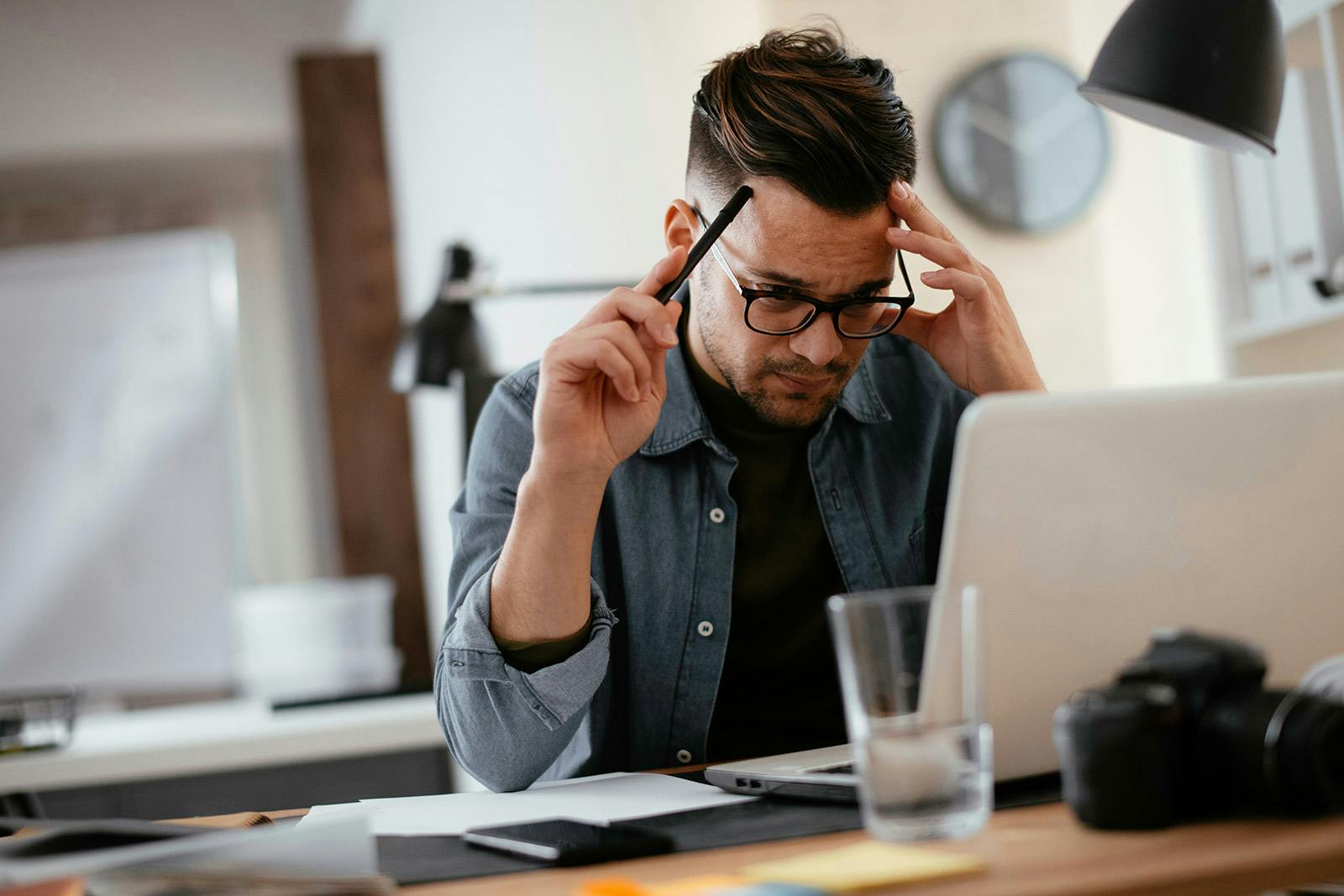 hombre con lentres frente a la computadora pensativo